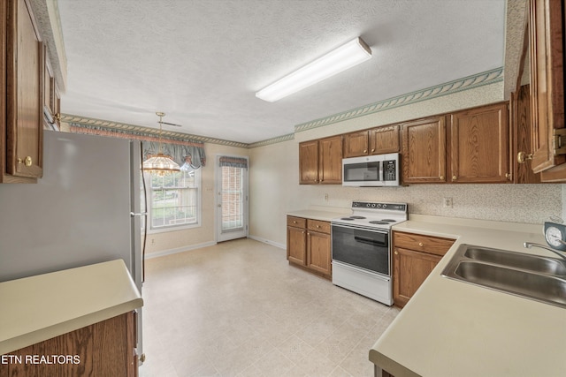 3804 Whitworth Dr, Knoxville, TN 37938 - kitchen with a sink, brown cabinets, light countertops, stainless steel microwave, and white electric stove
