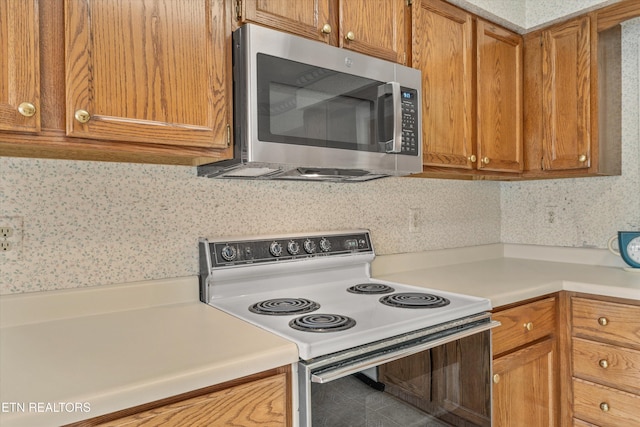 3804 Whitworth Dr, Knoxville, TN 37938 - kitchen featuring stainless steel microwave, light countertops, electric range, and brown cabinets