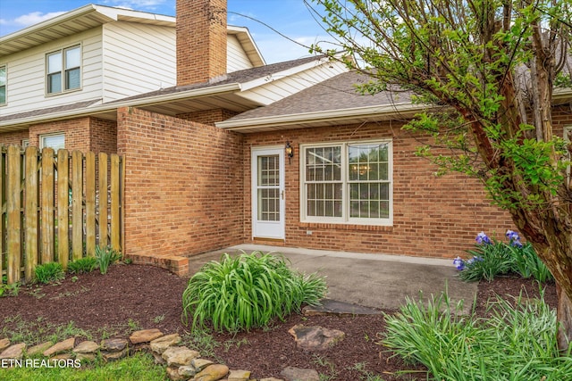 3804 Whitworth Dr, Knoxville, TN 37938 - view of property exterior with brick siding, a patio area, a chimney, fence, and roof with shingles
