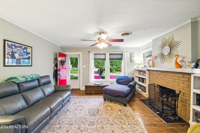 living room with a fireplace, wood finished floors, crown molding, and a ceiling fan