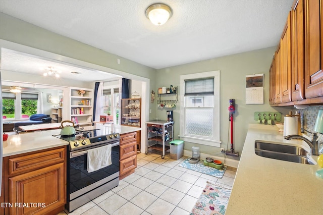 kitchen with light countertops, stainless steel range with electric cooktop, brown cabinetry, and a sink