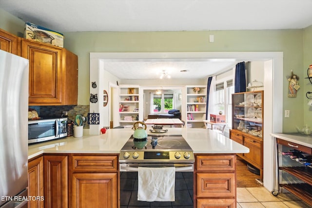 kitchen with light tile patterned floors, brown cabinets, appliances with stainless steel finishes, and light countertops