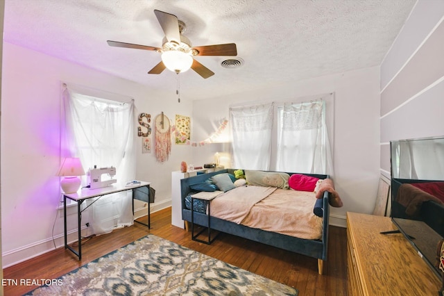 bedroom with a textured ceiling, visible vents, and hardwood / wood-style flooring