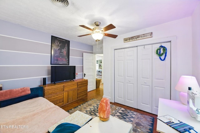 bedroom with visible vents, wood finished floors, a ceiling fan, and a closet