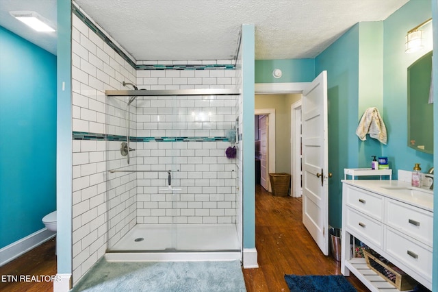 bathroom with a textured ceiling, a shower stall, and wood finished floors