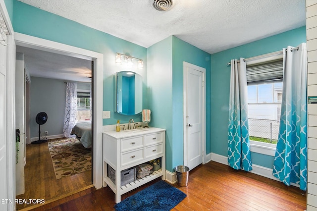 bedroom with visible vents, hardwood / wood-style flooring, a textured ceiling, and a sink