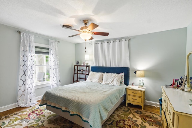 bedroom featuring baseboards, visible vents, wood finished floors, and a ceiling fan