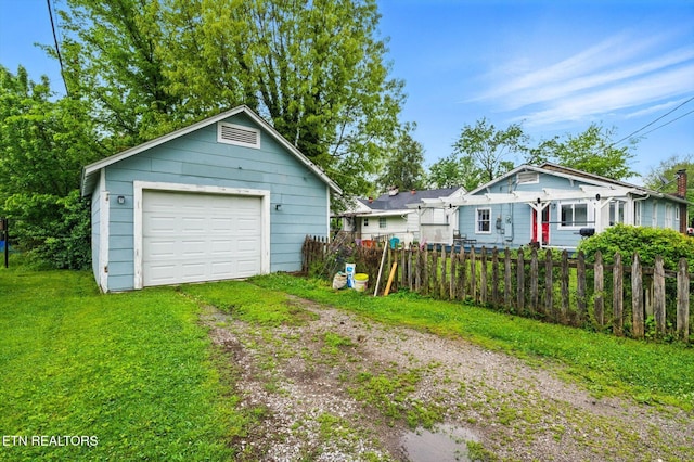 detached garage with fence and dirt driveway