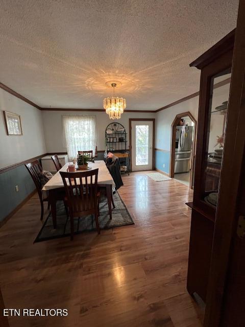 205 Hickory Ln, Jacksboro, TN 37757 - dining area with wood finished floors, a textured ceiling, crown molding, arched walkways, and a notable chandelier