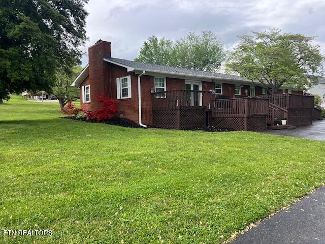 205 Hickory Ln, Jacksboro, TN 37757 - view of front of home with a chimney, a deck, brick siding, and a front lawn