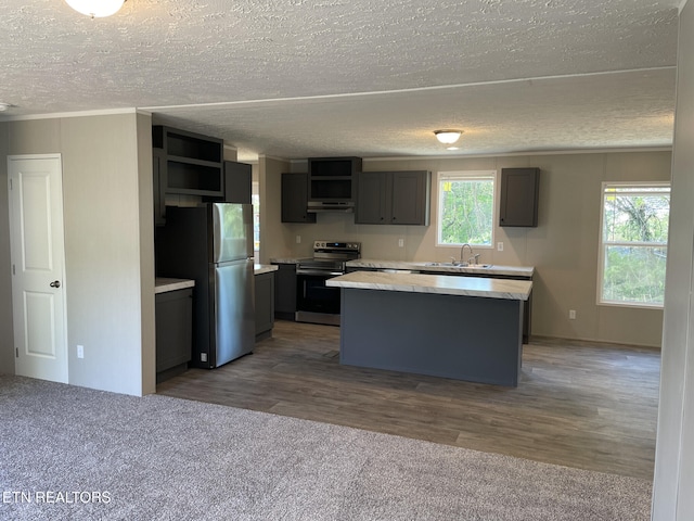 kitchen with open shelves, a sink, a center island, a textured ceiling, and appliances with stainless steel finishes