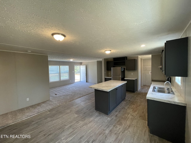 kitchen featuring a center island, light wood-style flooring, a sink, open floor plan, and freestanding refrigerator