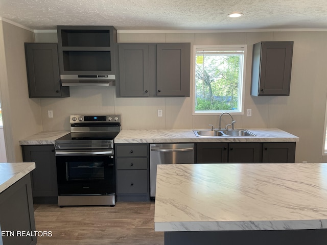 kitchen with a textured ceiling, appliances with stainless steel finishes, under cabinet range hood, and a sink