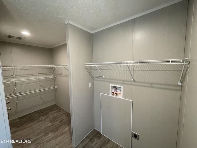 clothes washing area with crown molding, wood finished floors, hookup for a washing machine, hookup for an electric dryer, and visible vents
