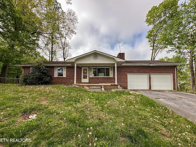 single story home featuring a chimney, aphalt driveway, a front lawn, an attached garage, and brick siding