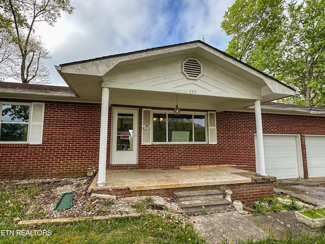 view of front of property with an attached garage, brick siding, a porch, and aphalt driveway