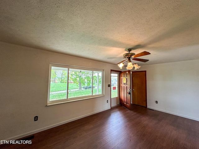 spare room with baseboards, a healthy amount of sunlight, ceiling fan, and dark wood finished floors