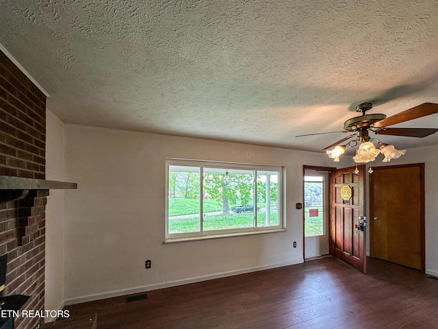 foyer entrance featuring a brick fireplace, a textured ceiling, and dark wood-type flooring