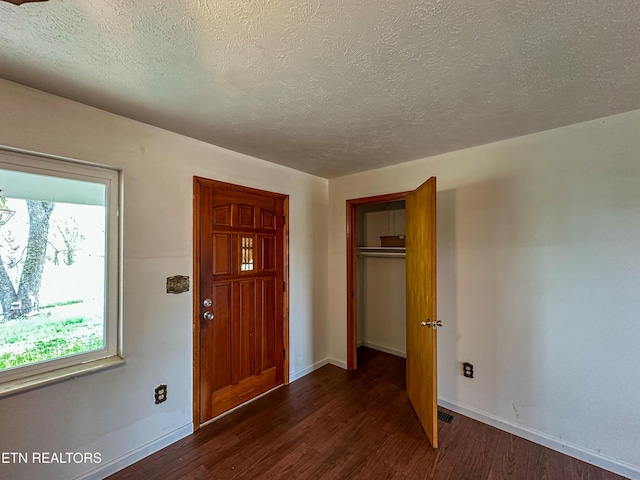 foyer with dark wood-type flooring, a textured ceiling, and baseboards