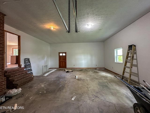 unfurnished living room with unfinished concrete floors and a textured ceiling