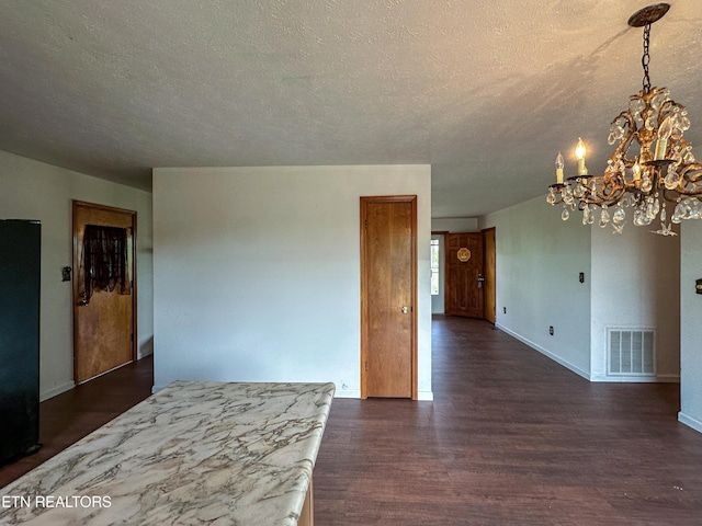 unfurnished room featuring baseboards, visible vents, an inviting chandelier, and dark wood-style flooring