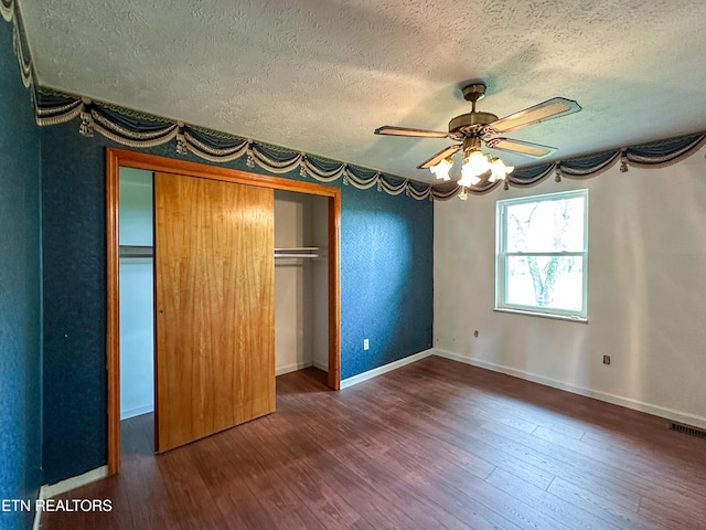unfurnished bedroom featuring a textured ceiling, hardwood / wood-style floors, a closet, baseboards, and visible vents