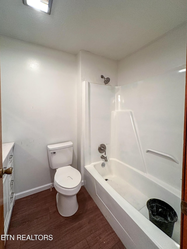 bathroom featuring washtub / shower combination, wood finished floors, toilet, vanity, and baseboards
