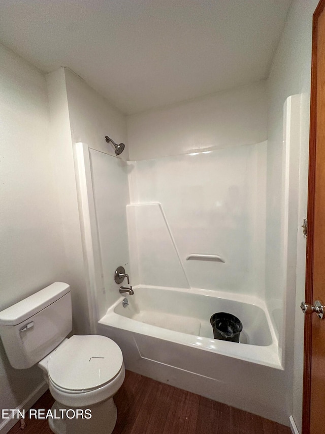 bathroom featuring toilet, wood finished floors, and tub / shower combination