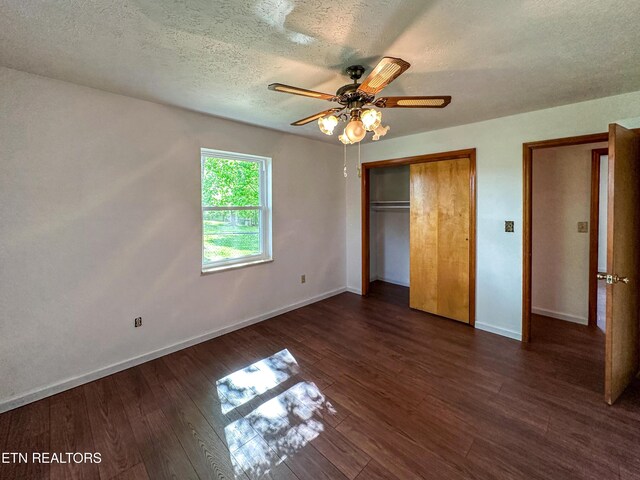 unfurnished bedroom featuring a ceiling fan, a textured ceiling, a closet, baseboards, and dark wood-style flooring