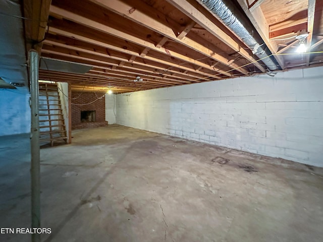 unfinished basement with a brick fireplace