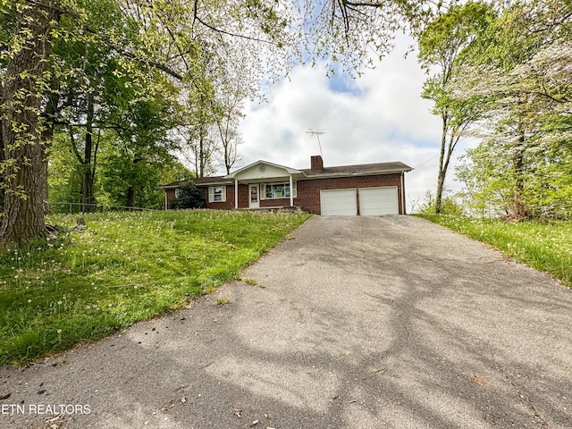 single story home with a chimney, aphalt driveway, an attached garage, fence, and brick siding
