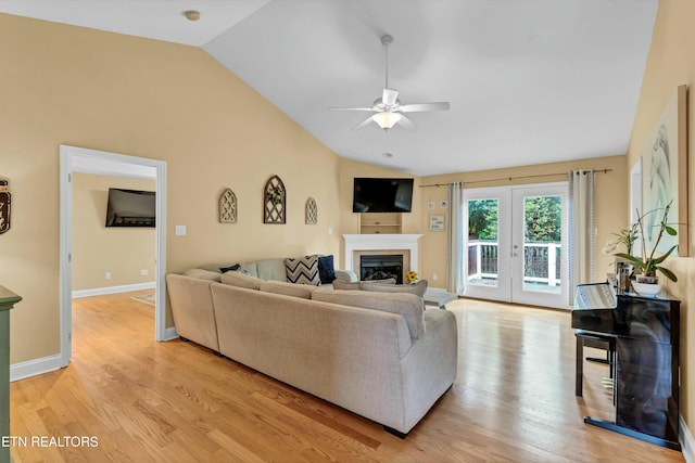 living area featuring a glass covered fireplace, ceiling fan, light wood-style flooring, and lofted ceiling