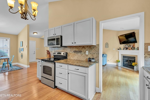 kitchen featuring an inviting chandelier, decorative backsplash, light wood finished floors, and appliances with stainless steel finishes