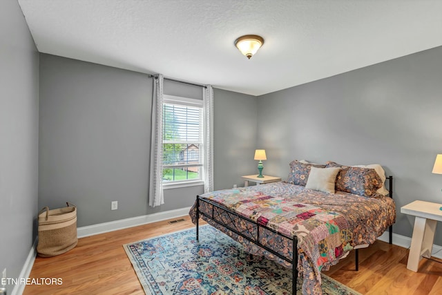 bedroom featuring baseboards, visible vents, and wood finished floors