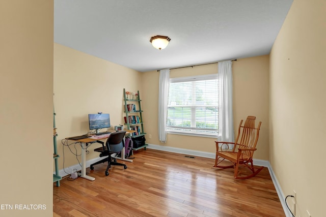 office area with baseboards, visible vents, and wood finished floors