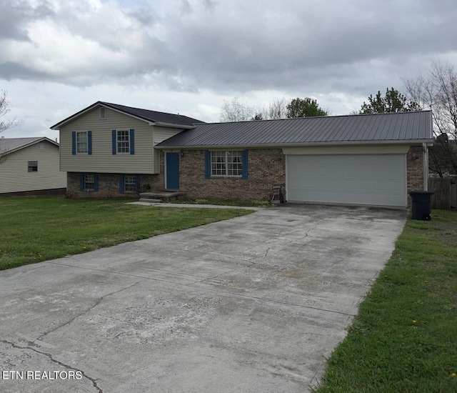 tri-level home with a front lawn, driveway, an attached garage, metal roof, and brick siding
