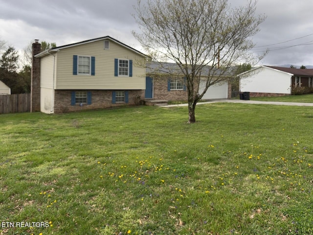 split level home with a chimney, fence, a front lawn, concrete driveway, and an attached garage
