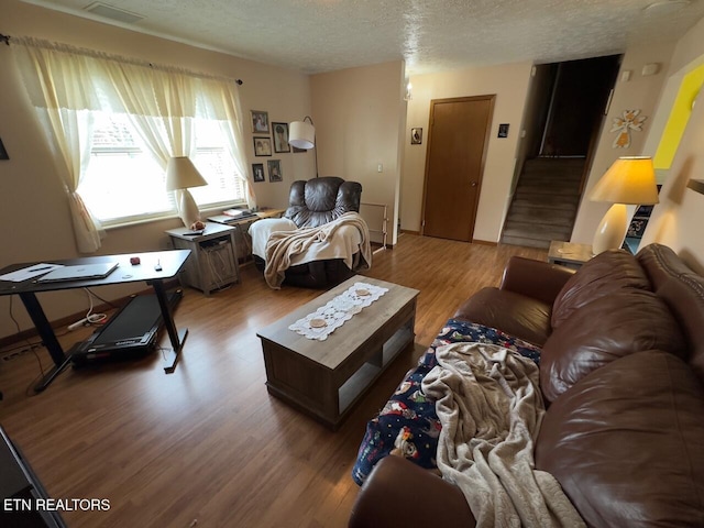 living area with visible vents, wood finished floors, and a textured ceiling