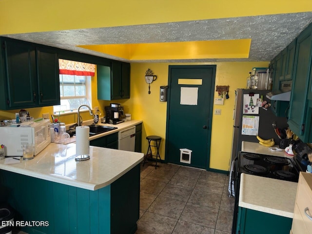 kitchen featuring a sink, white appliances, light countertops, a peninsula, and green cabinetry