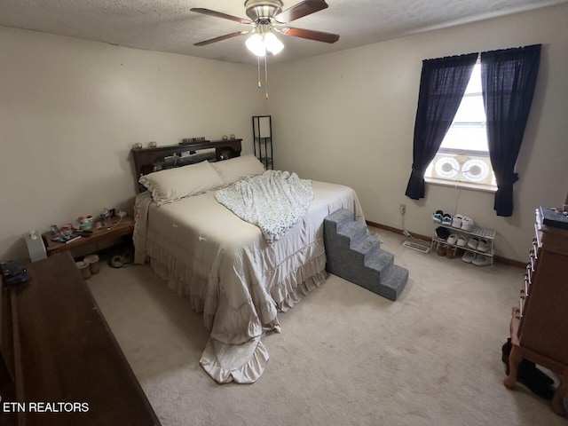 carpeted bedroom featuring ceiling fan and a textured ceiling