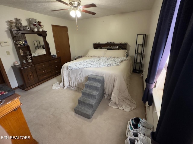 bedroom featuring ceiling fan, a textured ceiling, and light carpet