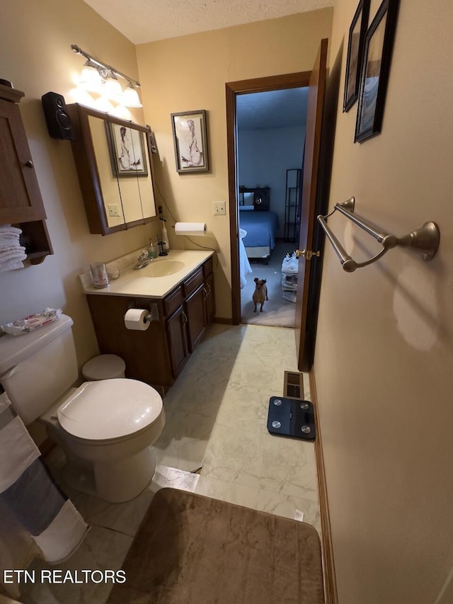 bathroom with marble finish floor, toilet, and vanity