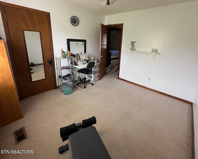 carpeted home office featuring baseboards, a ceiling fan, and visible vents