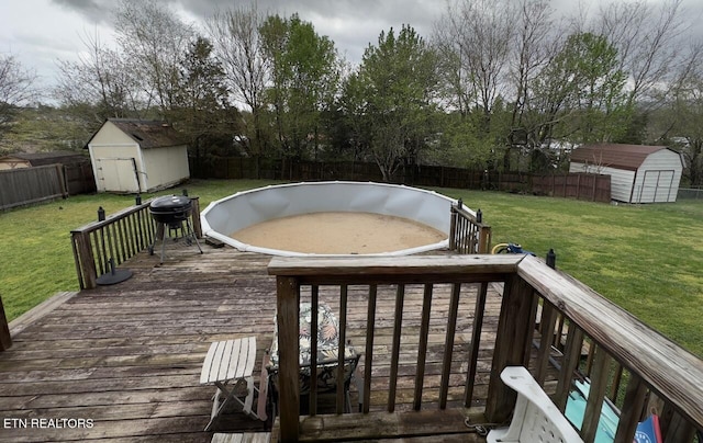 wooden deck with a fenced backyard, an outdoor structure, a yard, and a storage shed