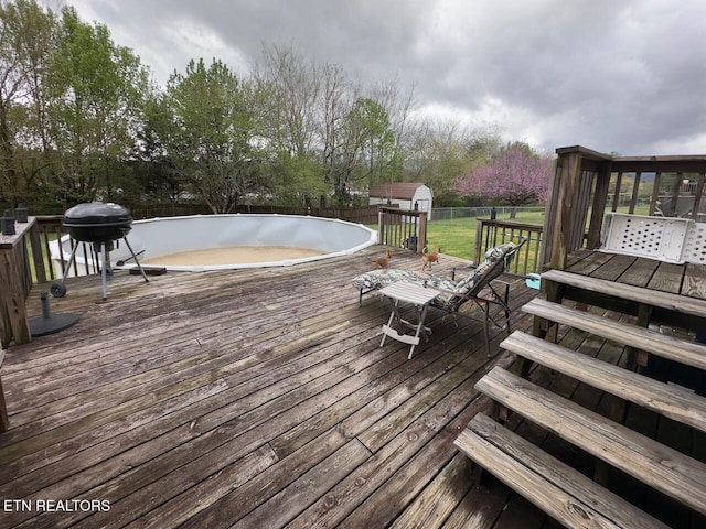 wooden terrace featuring a lawn, a fenced backyard, a storage unit, and an outdoor structure