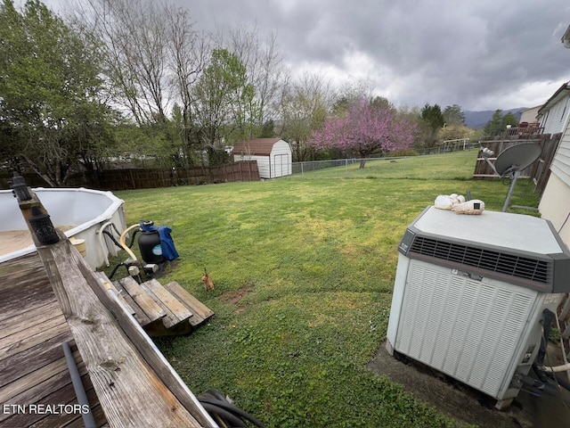 view of yard featuring a fenced backyard, central air condition unit, an outbuilding, and a shed
