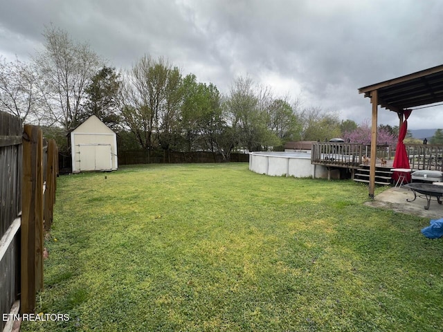 view of yard with a fenced backyard, a deck, a shed, and a fenced in pool