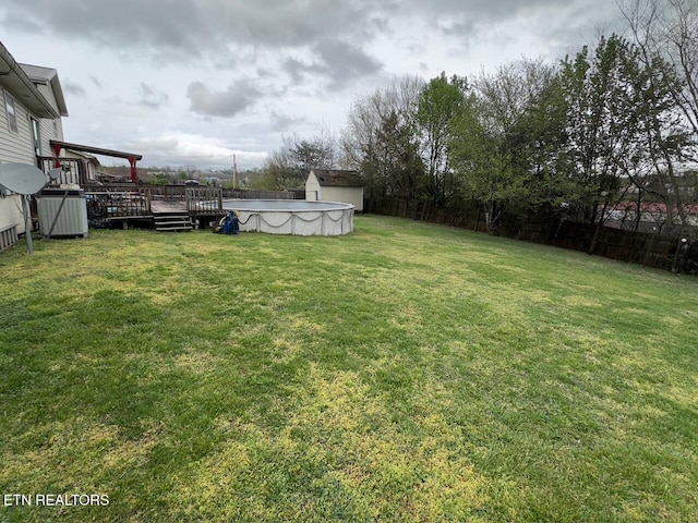 view of yard featuring a wooden deck, a fenced backyard, and an outdoor pool