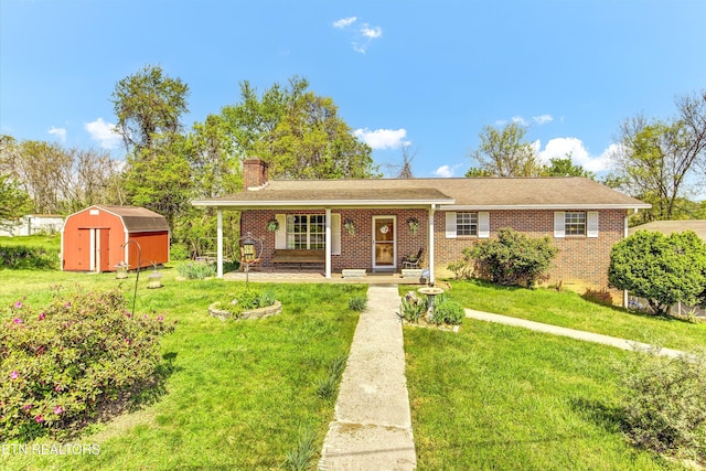ranch-style house featuring a front lawn, a storage unit, a chimney, and brick siding