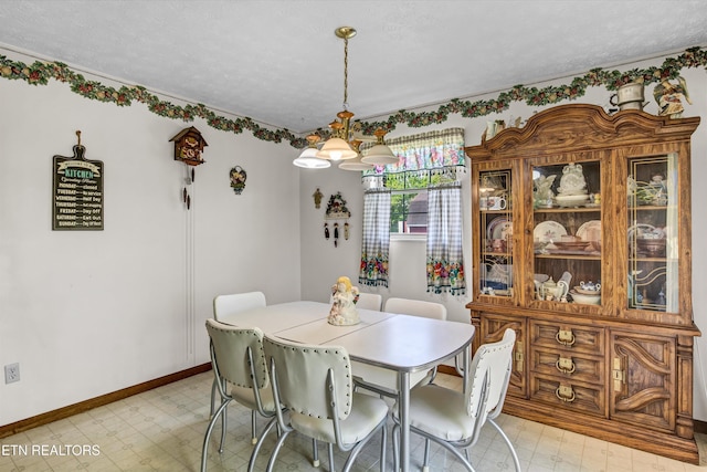 dining space with a textured ceiling, baseboards, and light floors